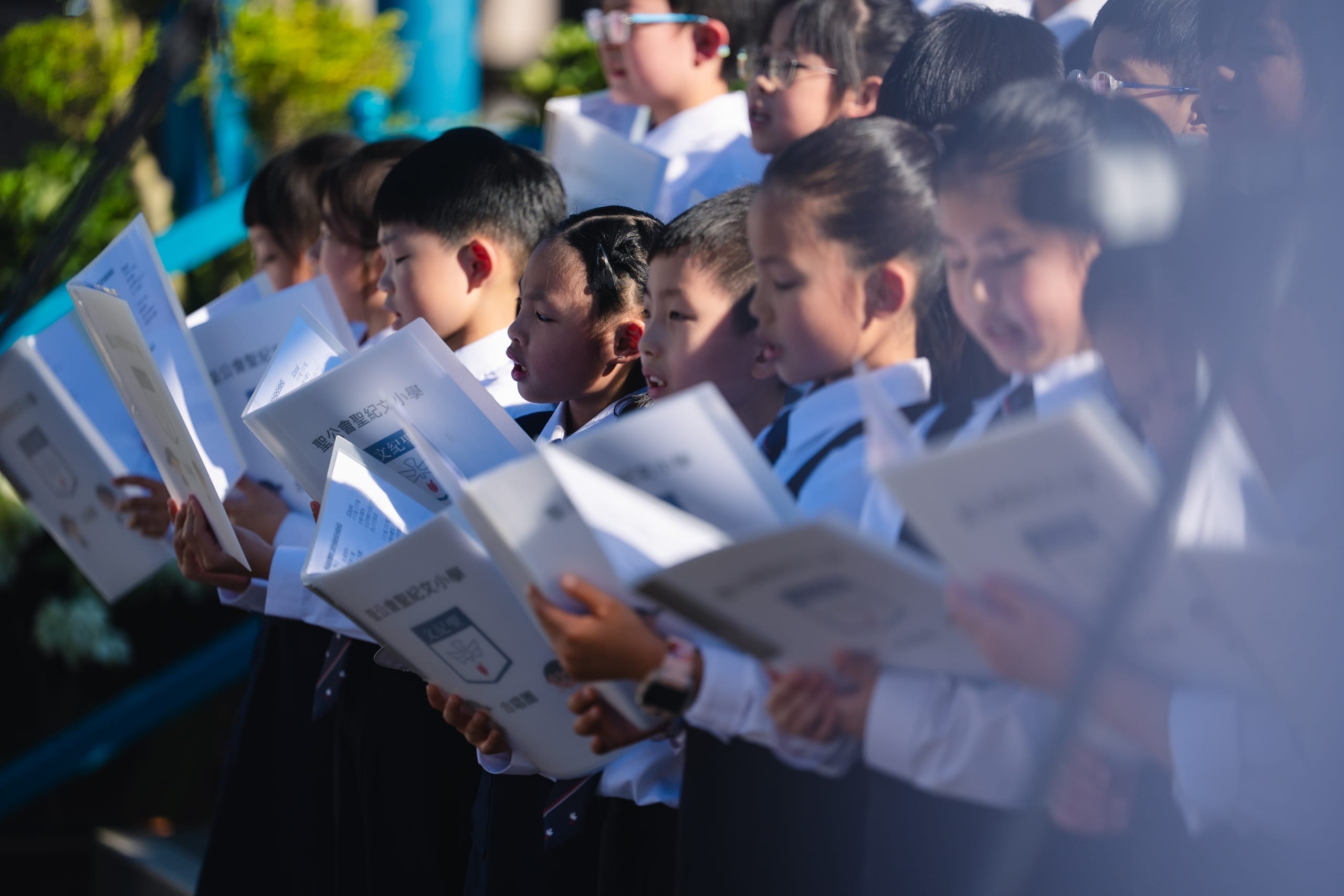 Primary school students singing from songbooks at an HKVC school choral event